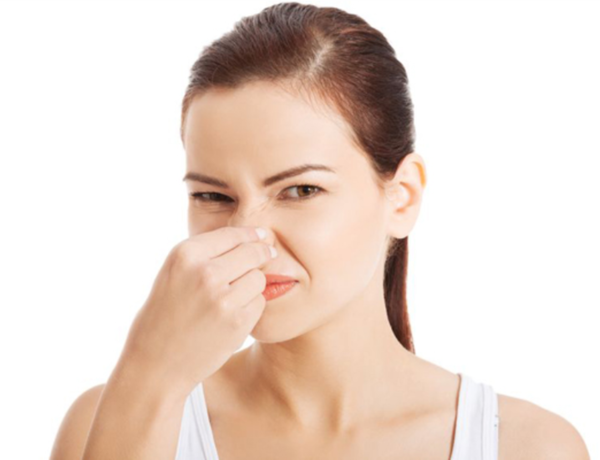 한 여성이 찡그린 표정으로 코를 틀어막고 있다.